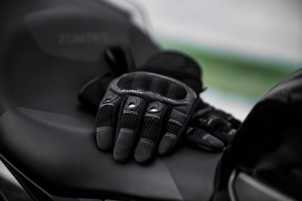 Close-up of black motorcycle gloves on a sleek motorcycle seat.