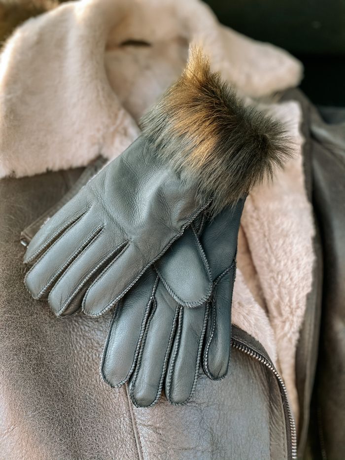 Close-up of stylish leather gloves on a sheepskin jacket, highlighting winter fashion.